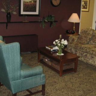 A cozy living room with a sofa, armchair, and coffee table arranged around a lamp and decorative items.