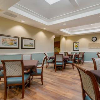 A modern dining area with neatly arranged tables and chairs, soft lighting, and artwork on the walls.