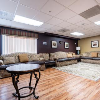 Spacious living room with large couches and a central coffee table, featuring hardwood floors and decorative wall art.