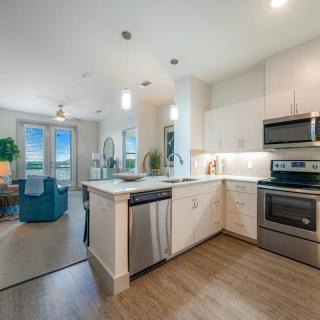 A modern kitchen with stainless steel appliances opens up to a bright, inviting living area.