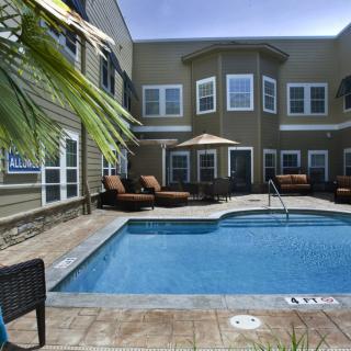 A serene outdoor swimming pool area with sun loungers at an apartment complex.