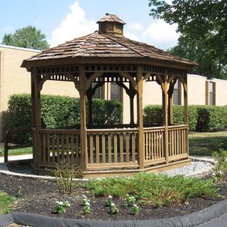 A wooden gazebo situated in a landscaped garden area.