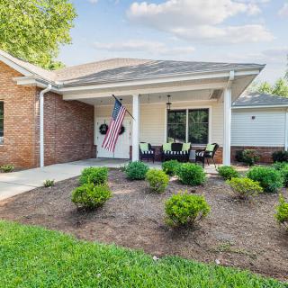 A cozy suburban house with a landscaped front yard and an inviting porch adorned with a flag.