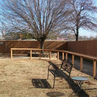 A winter backyard with a wooden fence, a tree without leaves, and a metal bench.