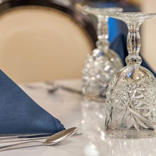 An elegantly set dining table with folded blue napkins and intricately designed glassware.