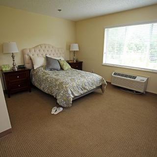 A cozy bedroom with a bed, lamps, and a window allowing natural light.