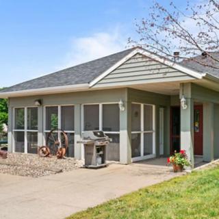 A cozy single-story house with a screened sunroom and tidy landscaping under a clear blue sky.
