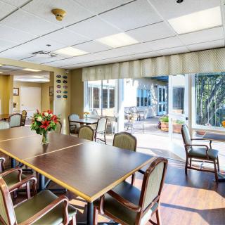 A well-lit conference room with a table and chairs, featuring a flower vase and large windows.