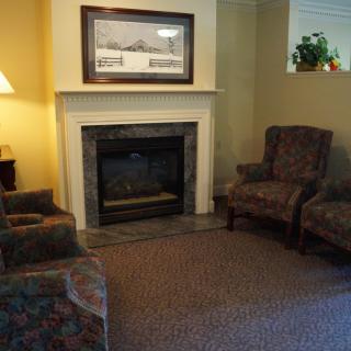 A cozy living room featuring a fireplace, two chairs, and warm lighting.