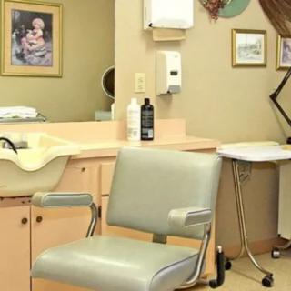 Interior view of a hair salon with a styling chair and sink.