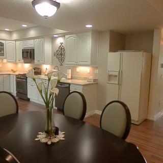 A modern kitchen and dining area featuring white cabinetry and a dark wooden dining table with flower centerpiece.