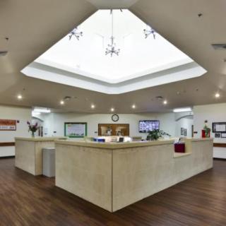 A hospital reception area with a central desk and bright overhead lighting.