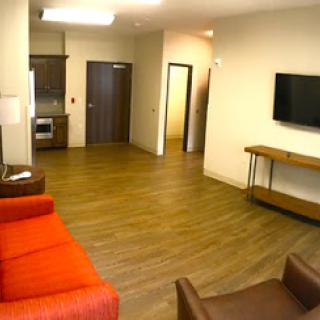 A spacious living area featuring modern furniture and a kitchenette.