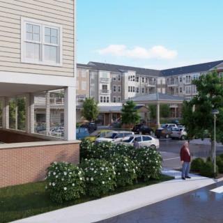 A residential apartment complex with a parking lot and landscaped surroundings.