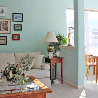 A cozy living room with a sofa, coffee table, and wall art under natural light.
