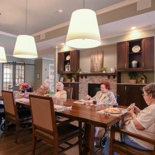 A group of seniors sitting around a dining table in a cozy, well-lit room.