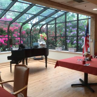 A cozy room featuring a grand piano and a garden view through large windows.