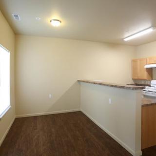 An empty kitchen and dining area with wood flooring and open layout.