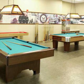 A game room featuring two billiard tables and wall decorations.