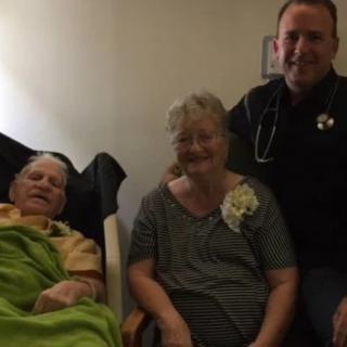 An elderly couple sitting in a hospital room with a healthcare professional.