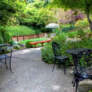 A tranquil garden patio with outdoor seating surrounded by lush greenery.