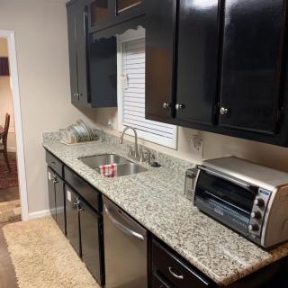 A modern kitchen with granite countertops and dark cabinets, featuring a sink and a toaster oven.