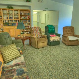 A cozy living room with several recliners and a well-stocked bookshelf.
