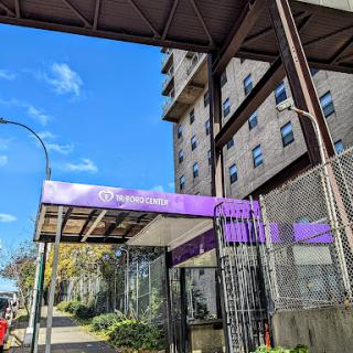 The entrance of a modern residential building featuring prominent purple signage.
