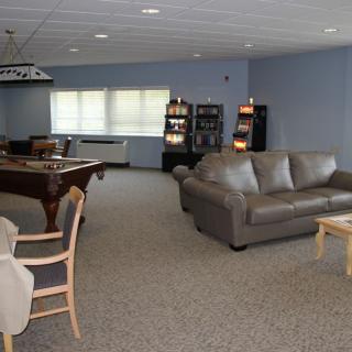 Spacious lounge area with a pool table, sofas, and bookshelves.