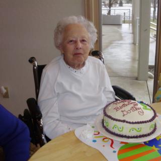 An elderly woman celebrating her birthday with a decorated cake.