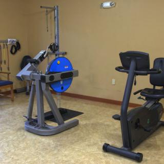 A gym with various exercise equipment, including a rowing machine and a recumbent bike.