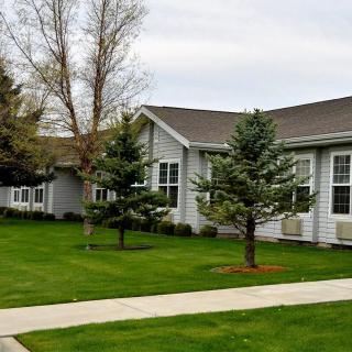 A suburban house with a well-maintained lawn, trees, and a pathway.