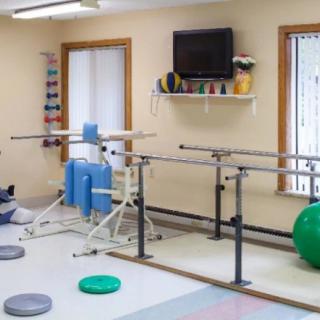 A rehabilitation room equipped with parallel bars and various exercise tools for physical therapy.