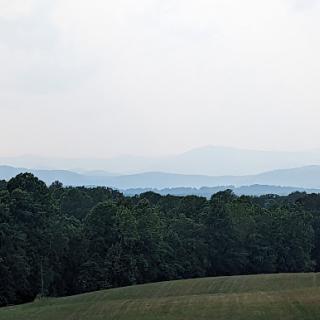A serene view of rolling hills and distant mountains shrouded in haze.
