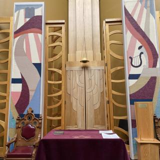 Interior view of a synagogue altar with colorful banners and symbolic designs.