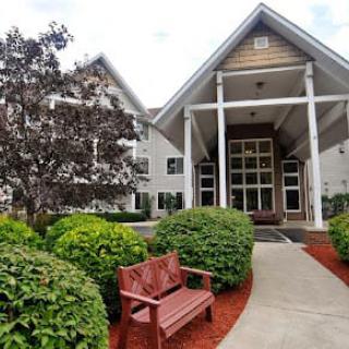 An inviting building entrance with benches and lush landscaping.