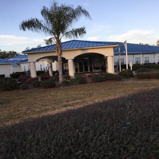 A modern building with a blue roof surrounded by lush landscaping and palm trees.
