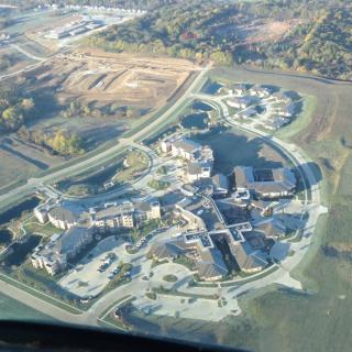 Aerial view of a building complex with surrounding roads and landscape.