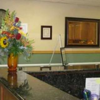 A reception desk with a flower arrangement and framed items on the wall.