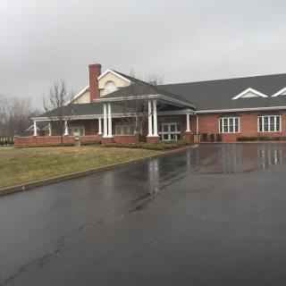 A residential building with a brick facade and a covered porch, set against an overcast sky.
