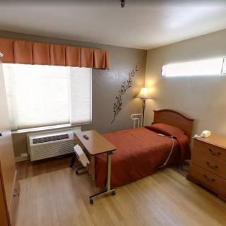 A simple and cozy bedroom with a single bed, dresser, and a bedside lamp.