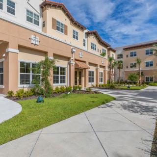 Modern apartment complex with well-maintained landscaping under a clear blue sky.