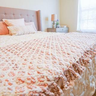 A cozy bedroom featuring a neatly arranged bed with a colorful quilt and pillows, creating a warm and inviting atmosphere.