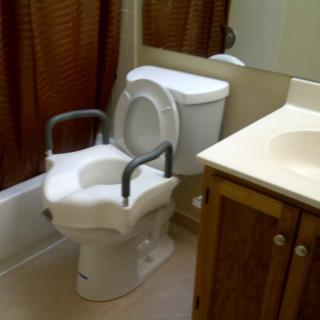 A bathroom with a toilet equipped with safety rails for accessibility.