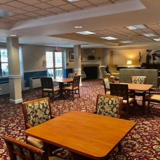 A spacious dining area with multiple tables and chairs, featuring a patterned carpet and ample lighting.
