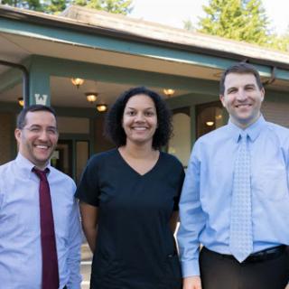 A cheerful group of three individuals posing together outside a building.