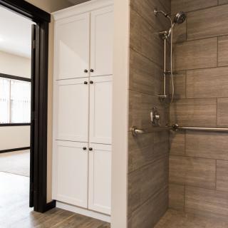 A modern bathroom featuring a tiled shower and white storage cabinets.
