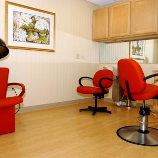 A cozy hair salon interior with vibrant red chairs and a wall mirror.