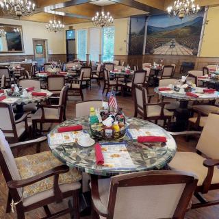 An elegant dining room with neatly arranged tables and chairs, adorned with chandeliers.