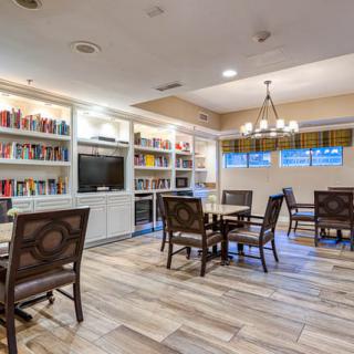 A cozy library room with bookshelves, tables, and comfortable chairs.